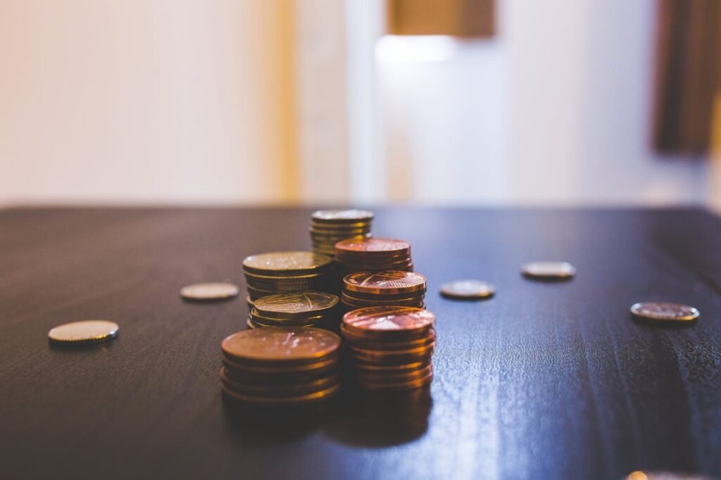 Close-up of various coins stacked on a dark table indoors.